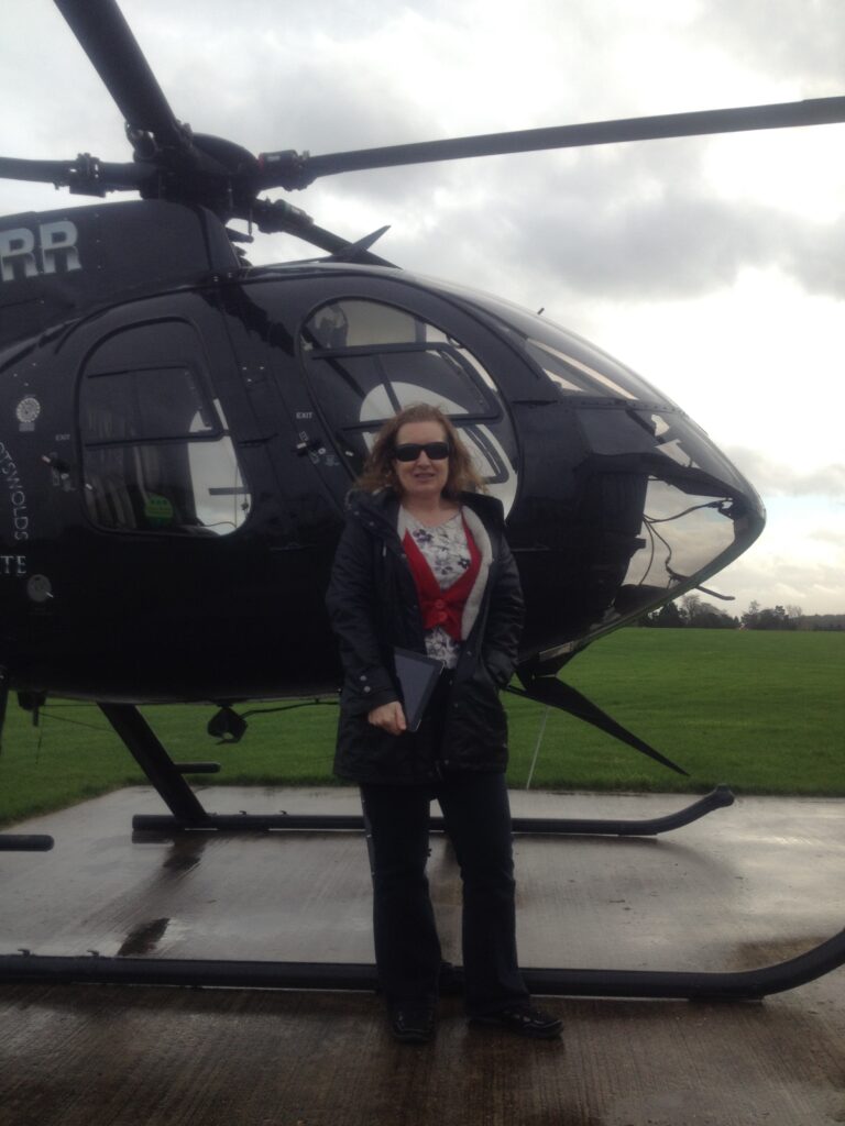 Sue Moorcroft stood in the front of a helicopter. 